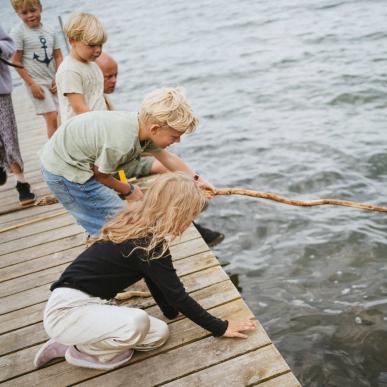 Børn fisker efter krabber ved stranden